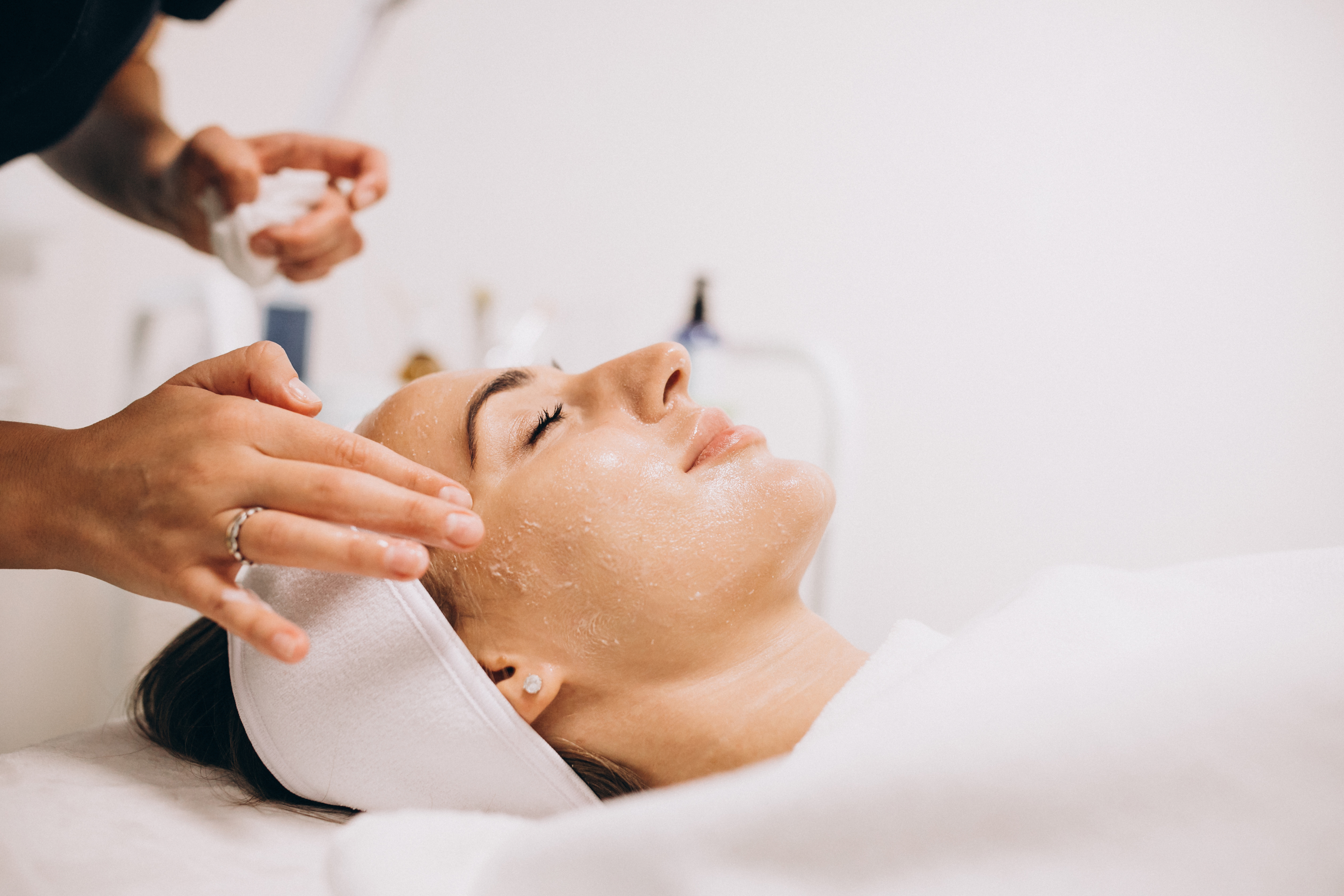 Cosmetologist cleaning face of woman in beauty salon